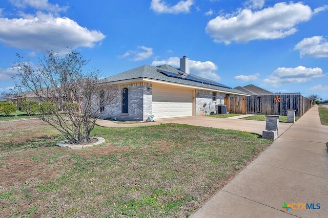 single story home with brick siding, solar panels, a front yard, a garage, and driveway