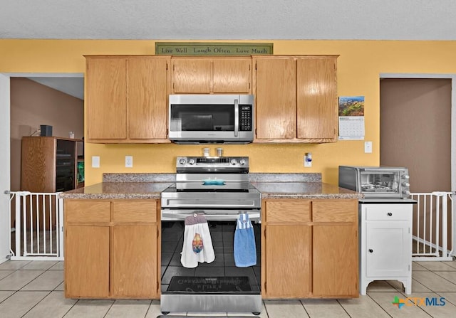 kitchen featuring light tile patterned floors, a toaster, and stainless steel appliances