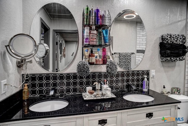 1319 County Road 339, Shiner, TX 77984 - bathroom with a textured wall, decorative backsplash, and double vanity