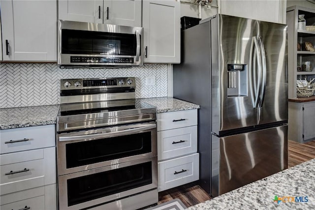 1319 County Road 339, Shiner, TX 77984 - kitchen featuring stainless steel appliances, light stone countertops, tasteful backsplash, and dark wood finished floors