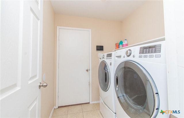 laundry area featuring laundry area, separate washer and dryer, light tile patterned flooring, and baseboards