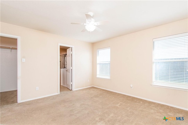 unfurnished bedroom with light carpet, baseboards, a walk in closet, and a closet