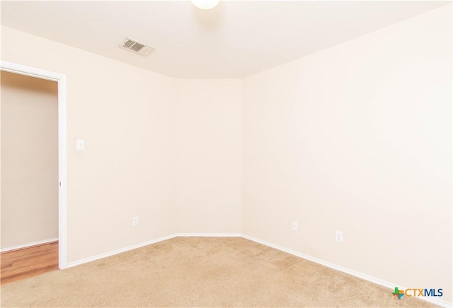 spare room featuring baseboards, visible vents, and light colored carpet