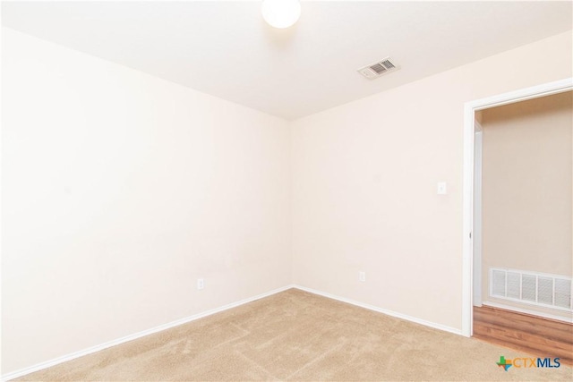 empty room with visible vents, light carpet, and baseboards