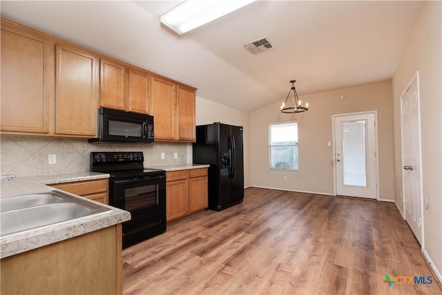 kitchen featuring lofted ceiling, a sink, visible vents, decorative backsplash, and black appliances