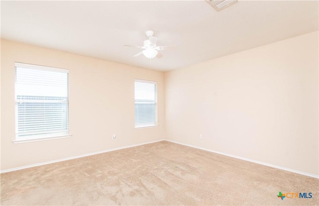 carpeted spare room featuring visible vents, ceiling fan, and baseboards