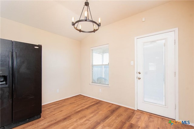 interior space featuring vaulted ceiling, wood finished floors, and a notable chandelier