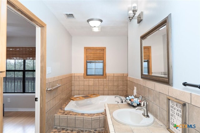 bathroom featuring sink and tiled tub