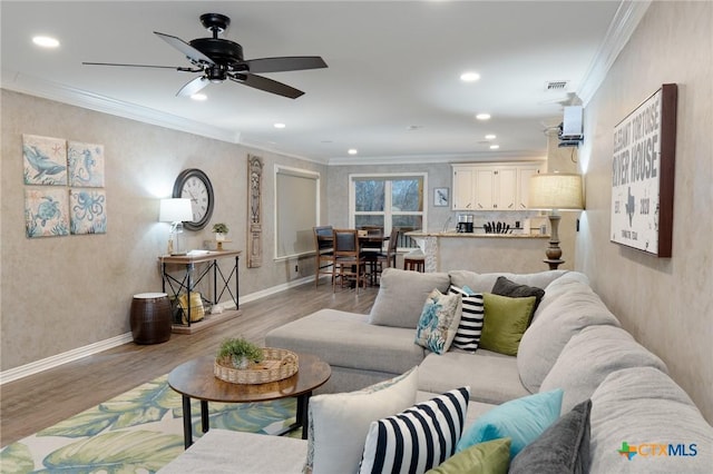 living room with crown molding, light hardwood / wood-style floors, and ceiling fan