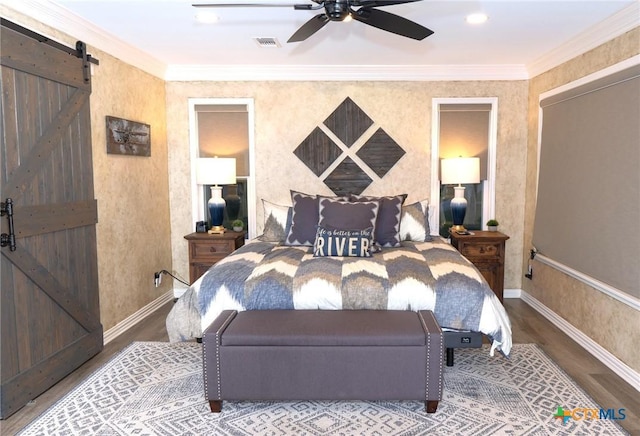 bedroom with wood-type flooring, ornamental molding, and a barn door