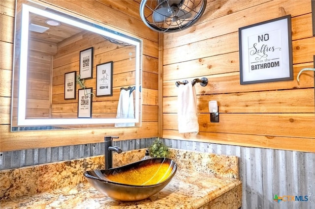 bathroom featuring vanity and wooden walls