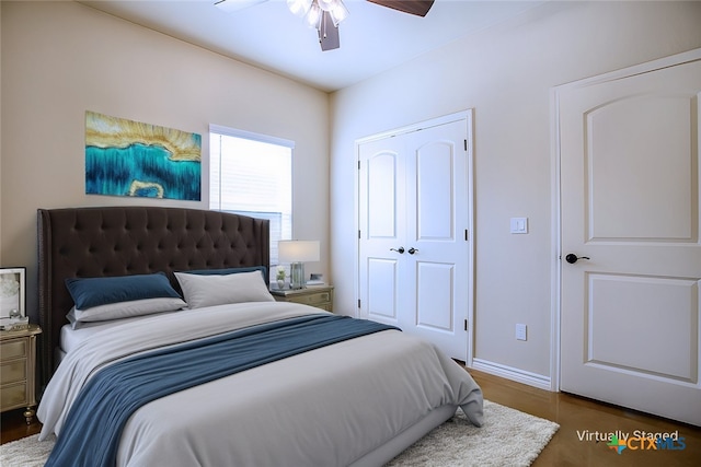 bedroom with dark hardwood / wood-style flooring, ceiling fan, and a closet