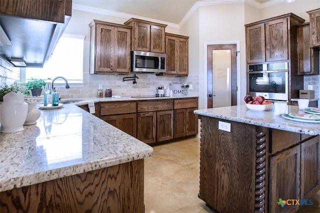 kitchen with light stone counters, ornamental molding, appliances with stainless steel finishes, dark brown cabinetry, and decorative backsplash