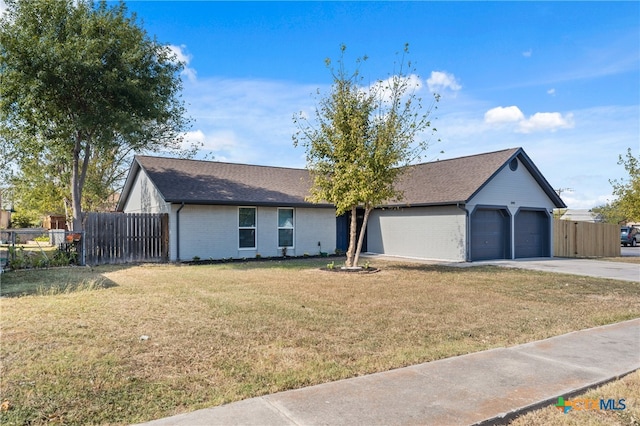 ranch-style house featuring a front yard, concrete driveway, fence, and an attached garage