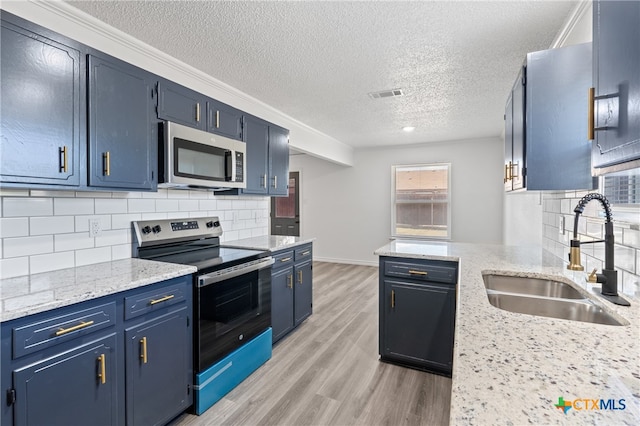 kitchen with blue cabinets, decorative backsplash, sink, light wood-type flooring, and appliances with stainless steel finishes