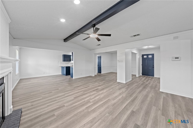 unfurnished living room featuring lofted ceiling with beams, a fireplace, a textured ceiling, ceiling fan, and light hardwood / wood-style flooring