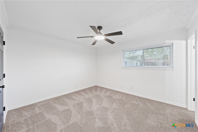 carpeted empty room with ceiling fan, a textured ceiling, and crown molding