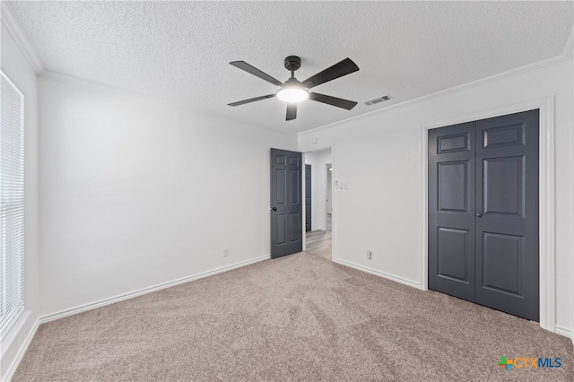 unfurnished bedroom featuring a closet, ornamental molding, a textured ceiling, light carpet, and ceiling fan