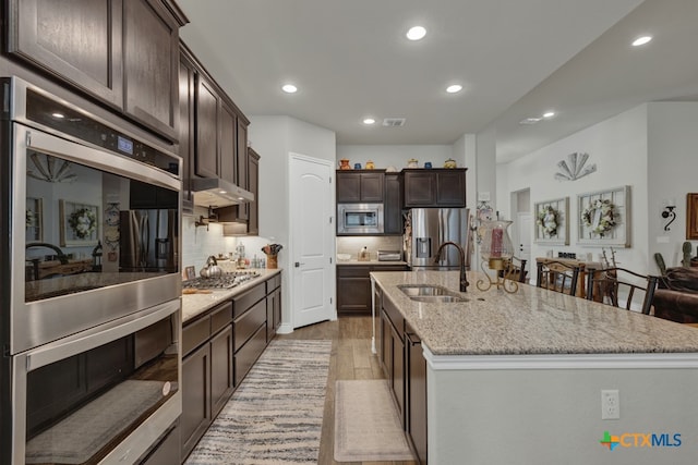 588 Vale Ct, New Braunfels, TX 78132 - kitchen with tasteful backsplash, a center island with sink, appliances with stainless steel finishes, sink, and light hardwood / wood-style flooring