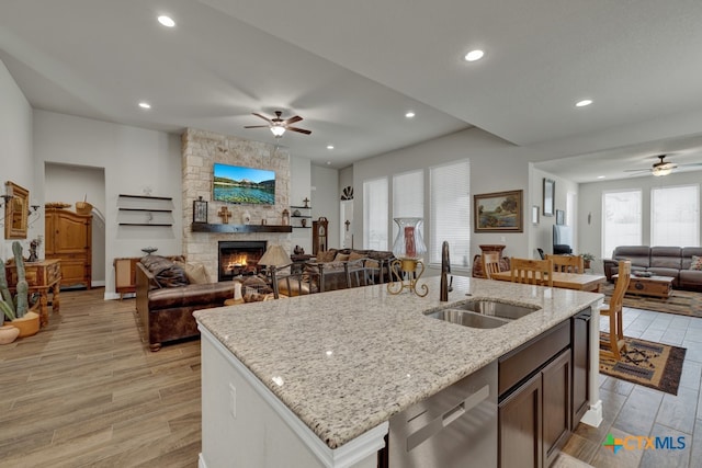 588 Vale Ct, New Braunfels, TX 78132 - kitchen with sink, an island with sink, stainless steel dishwasher, a fireplace, and light hardwood / wood-style flooring