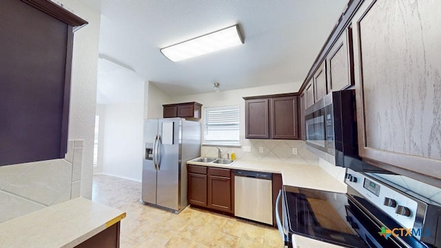 kitchen with appliances with stainless steel finishes, dark brown cabinetry, tasteful backsplash, and sink