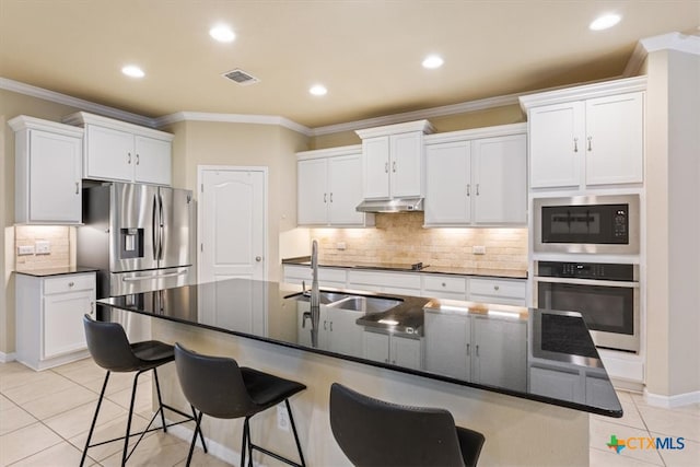 kitchen featuring a center island with sink, white cabinets, sink, light tile patterned floors, and appliances with stainless steel finishes