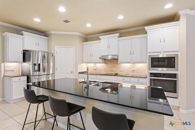 212 Lasata Ln, Belton, TX 76513 - kitchen featuring appliances with stainless steel finishes, a sink, under cabinet range hood, light tile patterned floors, and a kitchen bar
