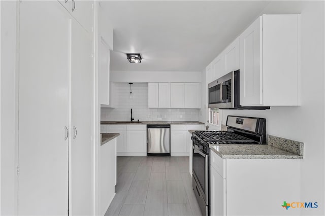 kitchen featuring white cabinetry, sink, light stone counters, decorative backsplash, and appliances with stainless steel finishes