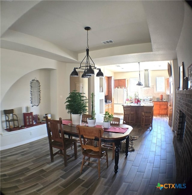 dining room featuring a fireplace and a raised ceiling