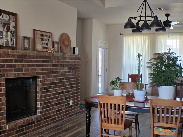 dining area featuring a brick fireplace and dark hardwood / wood-style floors