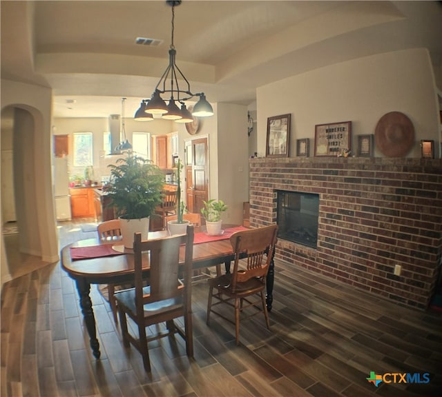 dining room featuring a tray ceiling and a fireplace