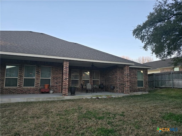 back of property with a yard, ceiling fan, and a patio area