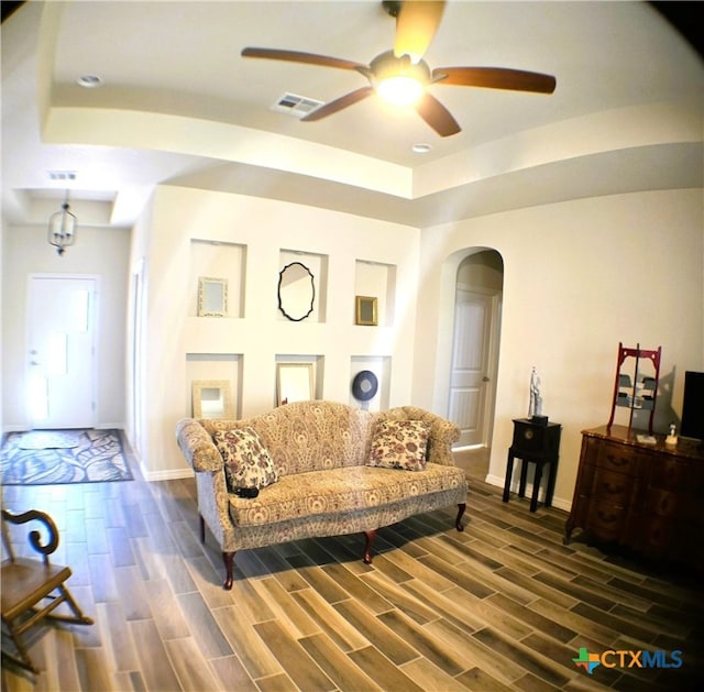 living room with a raised ceiling and ceiling fan