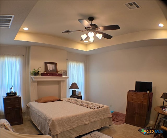 bedroom featuring multiple windows, a tray ceiling, and ceiling fan