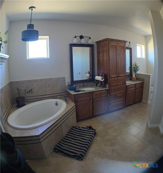 bathroom featuring vanity, tiled tub, and tile patterned flooring