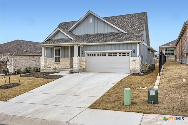 view of front of home with a garage, stone siding, roof with shingles, and driveway