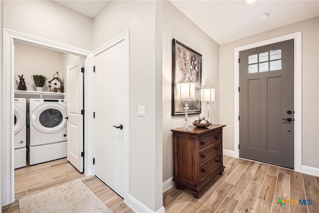 foyer featuring baseboards, wood finish floors, and washer and dryer