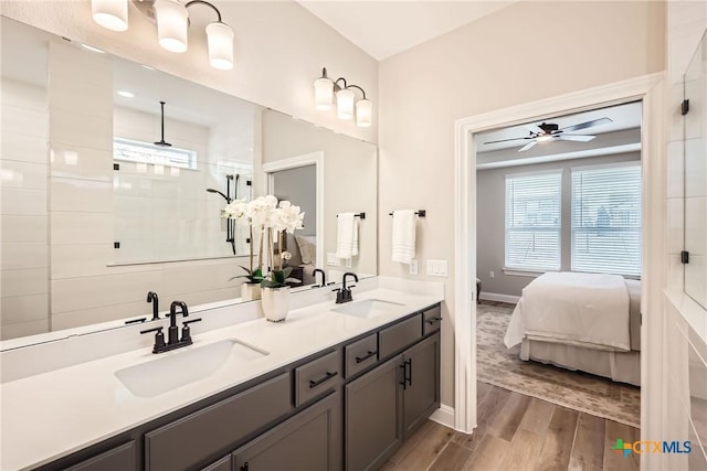 bathroom featuring double vanity, tiled shower, a sink, and wood finished floors