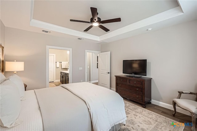 bedroom with visible vents, a raised ceiling, light wood-style flooring, and baseboards