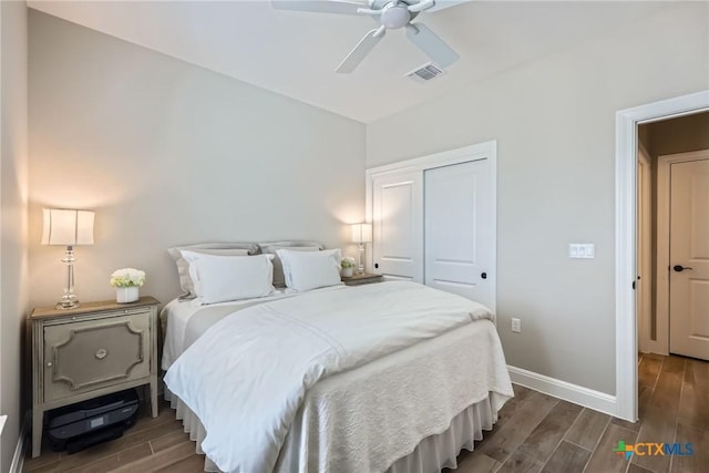 bedroom with baseboards, visible vents, a closet, and wood finish floors