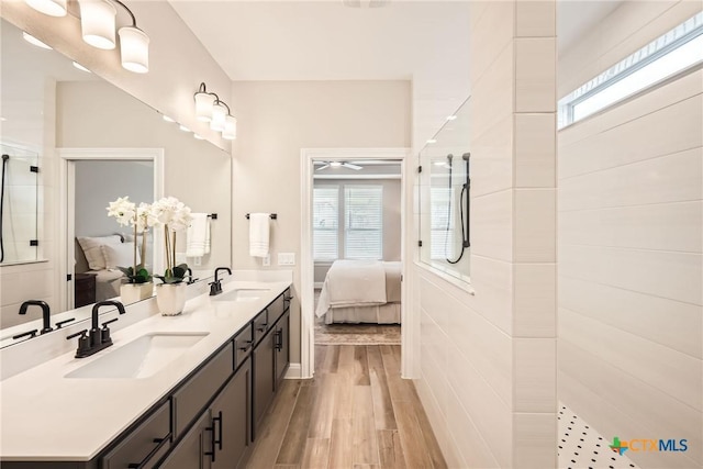 ensuite bathroom featuring ensuite bath, tiled shower, a sink, and wood finished floors