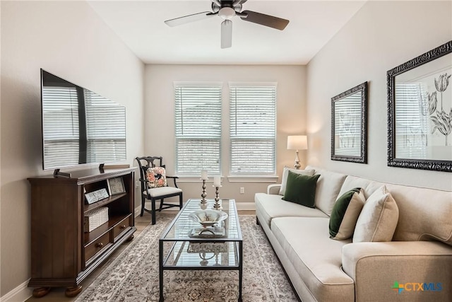 living area with a ceiling fan and baseboards