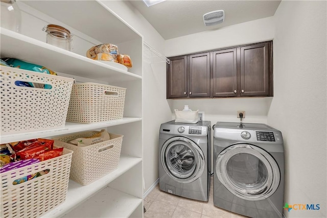 laundry room with cabinet space, light tile patterned floors, visible vents, and independent washer and dryer