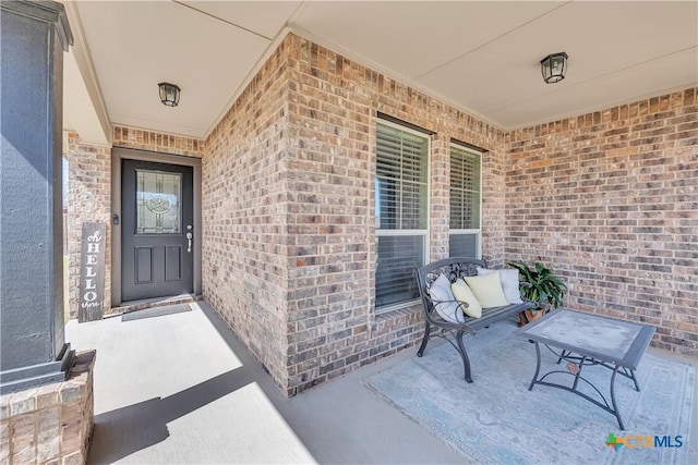 view of exterior entry with covered porch and brick siding