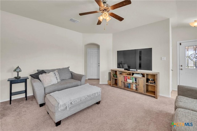 living area with a ceiling fan, visible vents, arched walkways, and carpet flooring