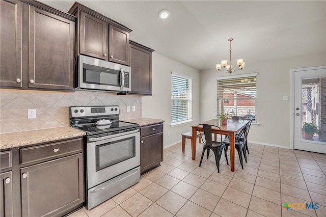 kitchen featuring tasteful backsplash, appliances with stainless steel finishes, dark brown cabinets, a chandelier, and light tile patterned flooring