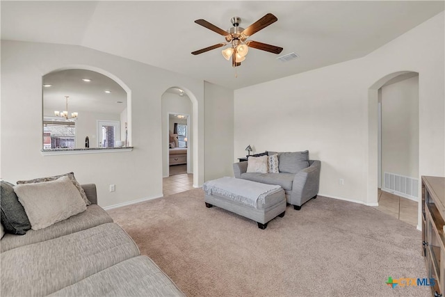 carpeted living area featuring ceiling fan with notable chandelier, baseboards, visible vents, and tile patterned floors