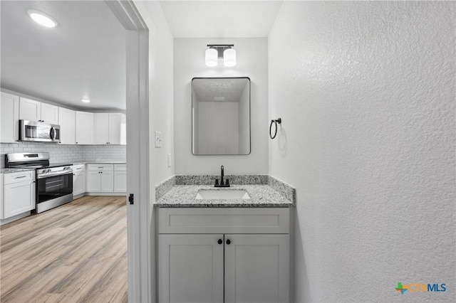 1005-1015 S 26th St, Temple, TX 76501 - bathroom featuring a sink, decorative backsplash, a textured wall, and wood finished floors