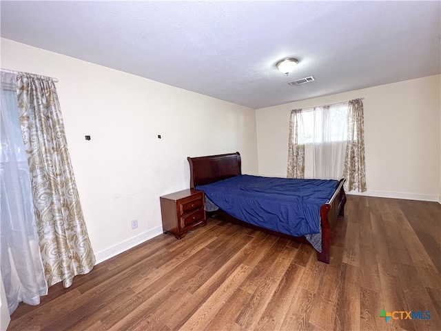 bedroom with a textured ceiling and dark hardwood / wood-style flooring