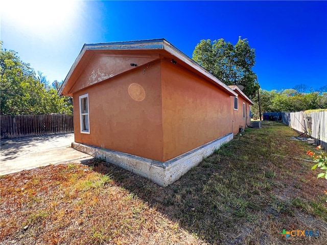 view of property exterior featuring central AC unit, a lawn, and a patio area